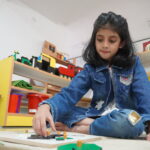 Girl working with learning materials on a mat in the classroom