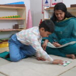 Teacher and child working together on the floor at Krish Elite