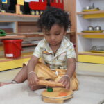 Young boy exploring learning materials near a classroom shelf