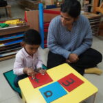 Child working on a colourful board with red and blue pieces