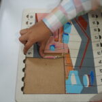 Close-up of a child's hands fitting pieces into a wooden frame