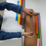 Child arranging colourful rods in order
