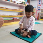 Boy in a white shirt concentrating on materials laid out on a mat