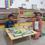 Children playing with a large map puzzle at a low table
