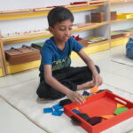 Boy working with a red tray of learning materials