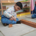 Boy concentrating on a floor activity with wooden materials