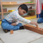 Boy arranging long wooden rods on the classroom floor