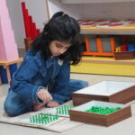 Girl focused on a tray activity on the classroom floor