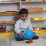 Boy examining a blue ball during a learning activity